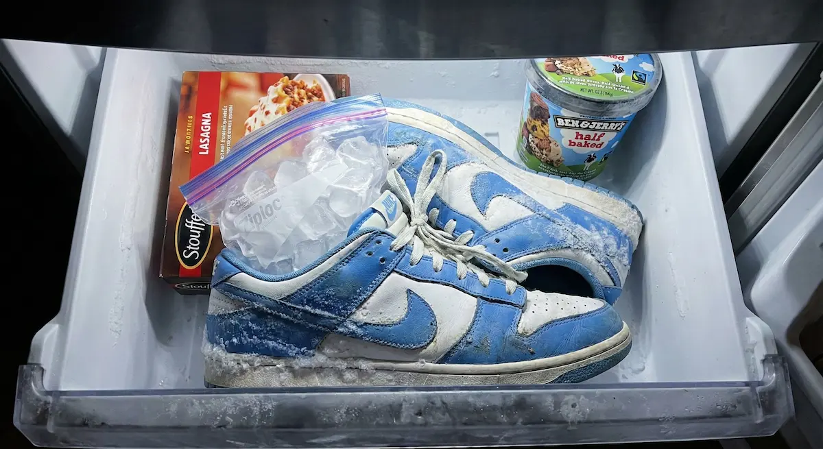 Tênis Nike azul dentro da gaveta do congelador com sacos de gelo dentro para alargar o calçado, posicionado ao lado de lasanha e sorvete.